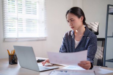 İş kadını finans belgesini kontrol ediyor ve yeni iş dünyasının strateji pazarlaması hakkında çalışırken ve analiz yaparken klavye bilgisayarına bilgi yazma projesine yatırım yapmayı düşünüyor.