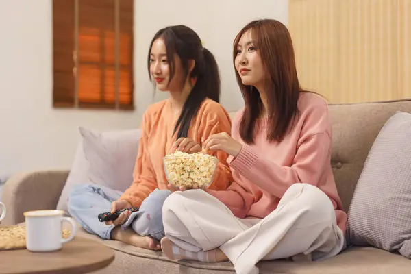 Ev konseptinde yaşam tarzı, LGBT lezbiyen çifti patlamış mısır yiyor ve birlikte film izliyorlar..