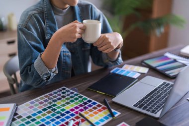 Grafik tasarımcı kadınlar kahve içerler ve logo grafik tasarımı hakkında düşünmek için laptopta veri okurlar..