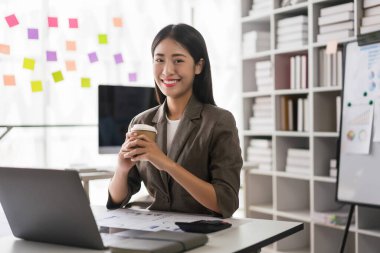 İş kadını laptopta çalışırken kahve içiyor ve iş dünyasının analiz stratejisine döküman gönderiyor..