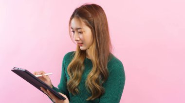 İş kadını pembe arka planda izole edilmiş tablete iş verileri yazıyor ve çalışıyor.