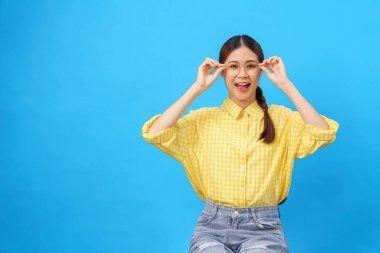 Kadınlar gülümsüyor ve tenha açık mavi arka planda boş alana dokunmak için ellerini kullanıyor..