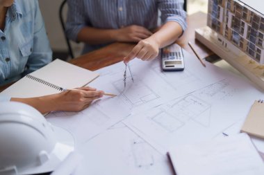 İki mimar proje inşaatı ve planda bölücü pusula kullanımını tartışır.