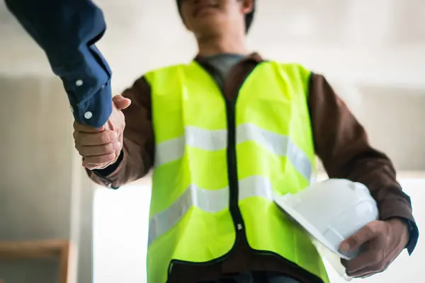 İki mühendis inşaat alanında başarılı bir şekilde çalıştıktan sonra el sıkışıyor..