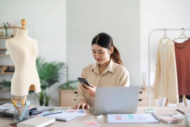 Moda tasarımcısı kadınlar akıllı telefondan yaratıcı yeni koleksiyon için fotoğraf renk numunesi alıyorlar.