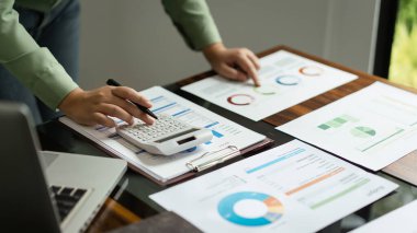Kadın muhasebeci, iş hesaplama finansmanı için belge üzerindeki sayıyı hesaplamak için hesap makinesi kullanır.