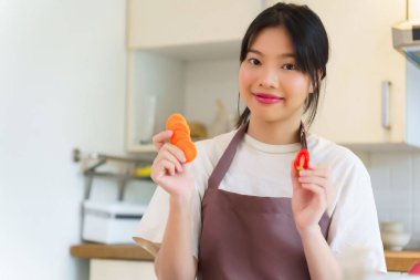 Domates ve havuç dilimleyen Asyalı kadınlar kahvaltı hazırlamak için taze sebzeler hazırlarken aynı zamanda evde mutfakta sağlıklı yiyecek yaşam tarzları hazırlıyorlar..