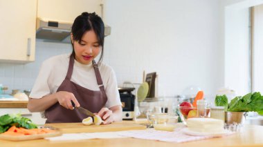 Asyalı kadınlar kaynatılmış yumurtayı panoda bıçakla kesiyorlar ve kahvaltı hazırlamak için taze sebzeleri dilimliyorlar. Evde, mutfakta sağlıklı yiyecek yaşam tarzları hazırlıyorlar..