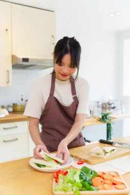 Asyalı kadınlar, kahvaltıdan sonra tabağa dilimlenmiş sandviç koyarken sebze ve haşlanmış yumurta salatasıyla lezzetli sandviçler yapıyorlar ve evde sağlıklı bir yaşam sürüyorlar..