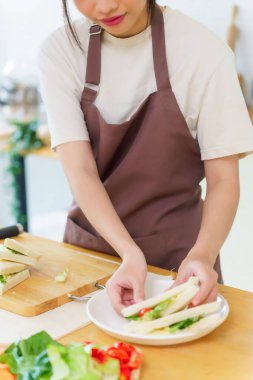 Asyalı kadınlar, kahvaltıdan sonra tabağa dilimlenmiş sandviç koyarken sebze ve haşlanmış yumurta salatasıyla lezzetli sandviçler yapıyorlar ve evde sağlıklı bir yaşam sürüyorlar..