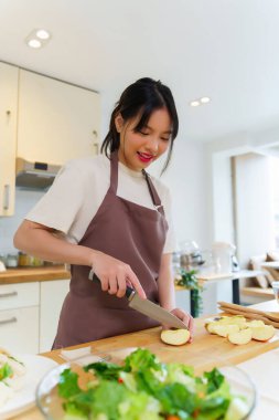 Asyalı kadınlar, kahvaltı hazırlamak için meyve ve taze sebze hazırlarken aynı zamanda mutfakta sağlıklı gıda yaşam biçimi hazırlamak için bıçakla elma dilimleri kesiyorlar..