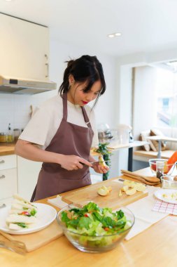 Asyalı kadınlar, kahvaltı hazırlamak için meyve ve taze sebze hazırlarken aynı zamanda mutfakta sağlıklı gıda yaşam biçimi hazırlamak için bıçakla elma dilimleri kesiyorlar..