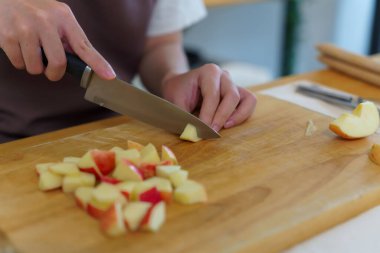 Asyalı kadınların bıçakla panoyu dilimlemek için elma keserken, kahvaltı yemeği ve salata hazırlarken evde sağlıklı bir yaşam sürmelerini sağlamak için meyve hazırlayan elleri..
