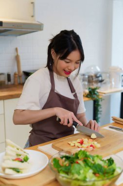 Asyalı kadınlar, kahvaltı yemeği ve salata hazırlamak için meyve ve sebze hazırlarken aynı zamanda mutfakta sağlıklı yemek yaşam tarzını hazırlamak için elmayı bıçakla doğruyorlar..