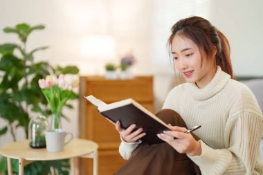 Kazaklı genç Asyalı kadınlar bilgi ve eğitimi öğrenmek için kitap okurken, aynı zamanda kanepede rahatlamak ve evde yavaş bir yaşam tarzıyla zaman geçirmek için etkinlik düzenliyorlar..