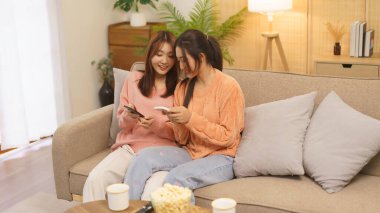 Ev konseptinde yaşam tarzı, LGBT lezbiyen çift birlikte rahatlamak için akıllı telefondan internette sörf yapıyor..