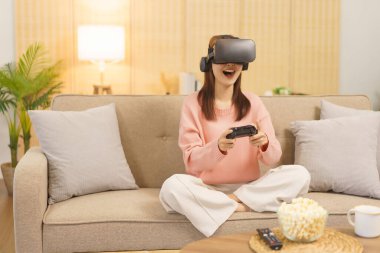 Lifestyle at home concept, LGBT lesbian women wears VR goggles and play game with joystick console.