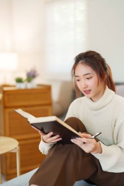 Kazaklı genç Asyalı kadınlar bilgi ve eğitimi öğrenmek için kitap okurken, aynı zamanda kanepede rahatlamak ve evde yavaş bir yaşam tarzıyla zaman geçirmek için etkinlik düzenliyorlar..