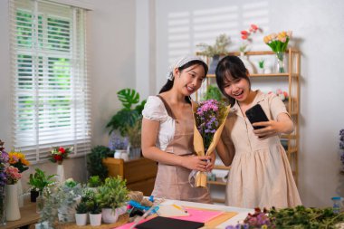 Güzel bir buketle selfie çeken iki çiçekçi canlı bir çiçekçide takım çalışmasını ve yaratıcılığı kutluyorlar..