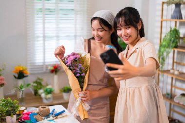 Güzel bir buketle selfie çeken iki çiçekçi canlı bir çiçekçide takım çalışmasını ve yaratıcılığı kutluyorlar..