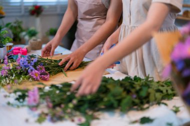 Çiçek desenlerini dikkatlice düzenleyen çiçekçiler, rahat bir çiçekçide titizlik ve yaratıcılık sergiliyorlar.