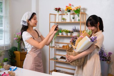 Bir çiçekçi çiçek buketinin fotoğrafını çekerken diğer bir çiçekçi canlı bir çiçekçide takım çalışmasına hayran kalıyor..