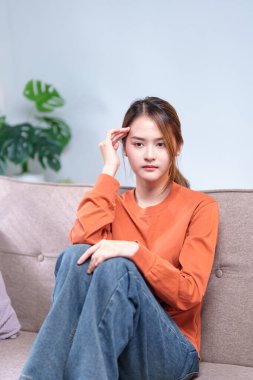 Düşünceli genç bir kadın bir kanepeye oturmuş, başını elinin üzerine yaslamış, derin düşüncelere dalmış..