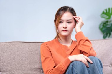 Düşünceli genç bir kadın bir kanepeye oturmuş, başını elinin üzerine yaslamış, derin düşüncelere dalmış..