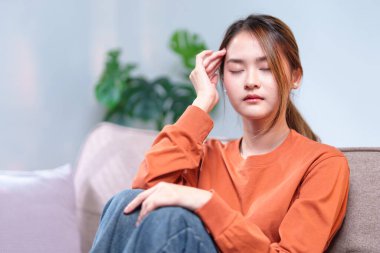 Düşünceli genç bir kadın bir kanepeye oturmuş, başını elinin üzerine yaslamış, derin düşüncelere dalmış..