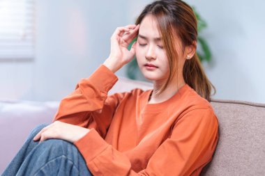 Düşünceli genç bir kadın bir kanepeye oturmuş, başını elinin üzerine yaslamış, derin düşüncelere dalmış..