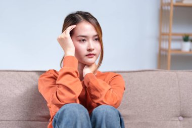 Düşünceli genç bir kadın bir kanepeye oturmuş, başını elinin üzerine yaslamış, derin düşüncelere dalmış..