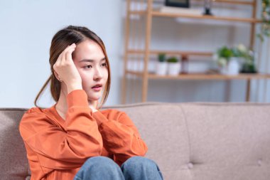 Düşünceli genç bir kadın bir kanepeye oturmuş, başını elinin üzerine yaslamış, derin düşüncelere dalmış..