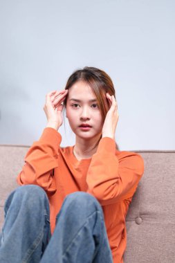 Düşünceli genç bir kadın bir kanepeye oturmuş, başını elinin üzerine yaslamış, derin düşüncelere dalmış..