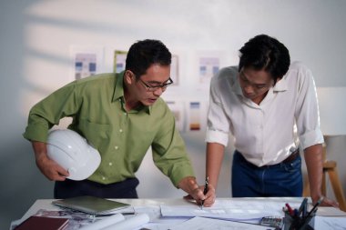 Mühendisler, toplantı masasında proje hesaplamaları, planlar, dizüstü bilgisayarlar ve teknik araçlar kullanarak birlikte çalışıyorlar..