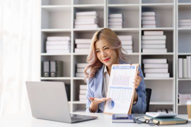 Kendine güvenen iş kadını, ofis çalışma alanında gülümseyerek veri raporunu panoya sunuyor.