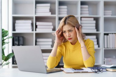 Stresli iş kadını ofis masasındaki hayal kırıklığıyla yüzünü örten iş baskısı yüzünden bunalmış.