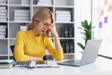 Stresli iş kadını ofis masasındaki hayal kırıklığıyla yüzünü örten iş baskısı yüzünden bunalmış.