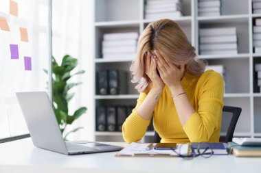 Stresli iş kadını ofis masasındaki hayal kırıklığıyla yüzünü örten iş baskısı yüzünden bunalmış.