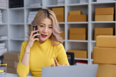 Ciddi bir kadın girişimci evden e-ticaret işini yönetirken telefonda teslimattan bahsediyor.