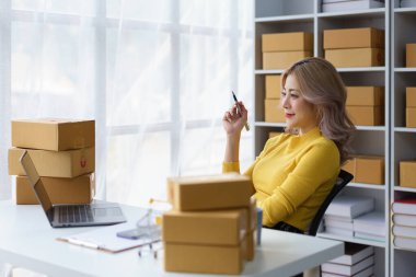 Düşünceli genç iş kadını planlama stratejisi. Etrafı konforlu ev tabanlı online mağazalarda nakliye kutularıyla çevrili.