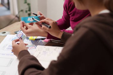 Asyalı kadınlar kullanıcı deneyimi üzerine odaklanmış bir mobil uygulama web sitesi için beyin fırtınası yaparak UI tasarımı üzerinde işbirliği yapıyorlar. Kullanıcı memnuniyeti için ux tasarımı planlanıyor