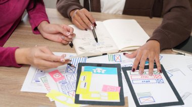 İki Asyalı kadın tasarımcı, yetişkin, bir Kullanıcı Arayüzü projesinde işbirliği yapıyor. Mobil Uygulama ve Web sitesi tasarımları için kullanıcı deneyimini geliştirmek için fikir çiziyorlar..