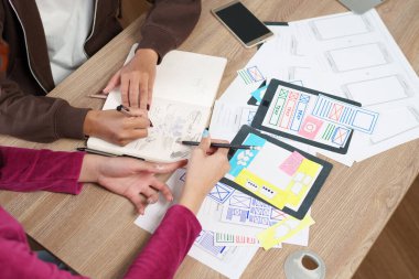 Asyalı genç tasarımcılar UI elemanlarını işbirliği içinde çizerek kullanıcı deneyimini geliştiriyorlar. Mobil uygulama arayüzü ve web sitesi yerleşimi kavramlarını araştırarak, Girişim için yenilikçi fikirleri teşvik ederler .