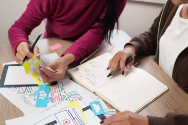 Yetişkin Asyalı kadınlar mobil uygulamalar için kullanıcı arayüzü tasarım fikirleri üzerinde işbirliği yapıyorlar. Dijital ürünler için kullanıcı deneyimini geliştirmek için başlangıç projeleri için beyin fırtınası oturumu.