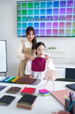 Kişisel renk analiz oturumu. Asyalı kadınlar, yetişkinler renk danışmanlığı alıyor. En iyi renkleri belirlemek için kumaş parçaları kullanan stilist. Doğru gölgeleri bul, doğal güzelliği arttır..