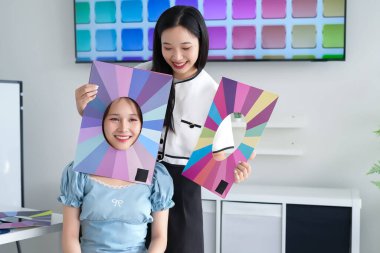 Genç Asyalı kadınlar kişisel renk analizinden geçiyor. Müşteri için en iyi renkleri belirlemek için renk örnekleri kullanan profesyonel renk danışmanı. Uzman renk tavsiyesiyle doğal güzelliği geliştirmek.