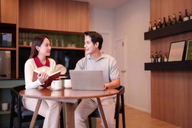 Genç bir Asyalı çift bir projeyi tartışıyor. Asyalı adam dizüstü bilgisayarı üzerinde çalışırken Asyalı kadın elinde bir kitap tutuyor. Takım çalışmasıyla birlikte gülümsüyorlar ve mutlular..