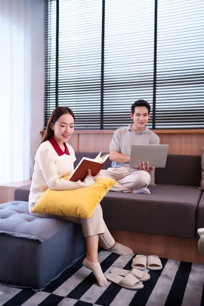 Yetişkin bir Asyalı çift evde huzurlu bir anın tadını çıkarıyor. Kadın kitap okumaya dalmış, erkek ise rahat oturma odasında dizüstü bilgisayarını kullanıyor.