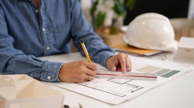 Asyalı yetişkin bir adam, uzman mimar yeteneklerini sergileyerek bir plan çiziyor. İnşaat planı, ev tasarımı planı ve zemin planı görünür. Proje sezgileri olan yetenekli bir mimar tasarımı.