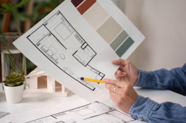 Yetişkin Asyalı mimarın elleri mimari taslak ve renk paletini sunar. O bir ev iç tasarımı tasarlıyor. Mimari plan önemli bir iç mimari tasarım.